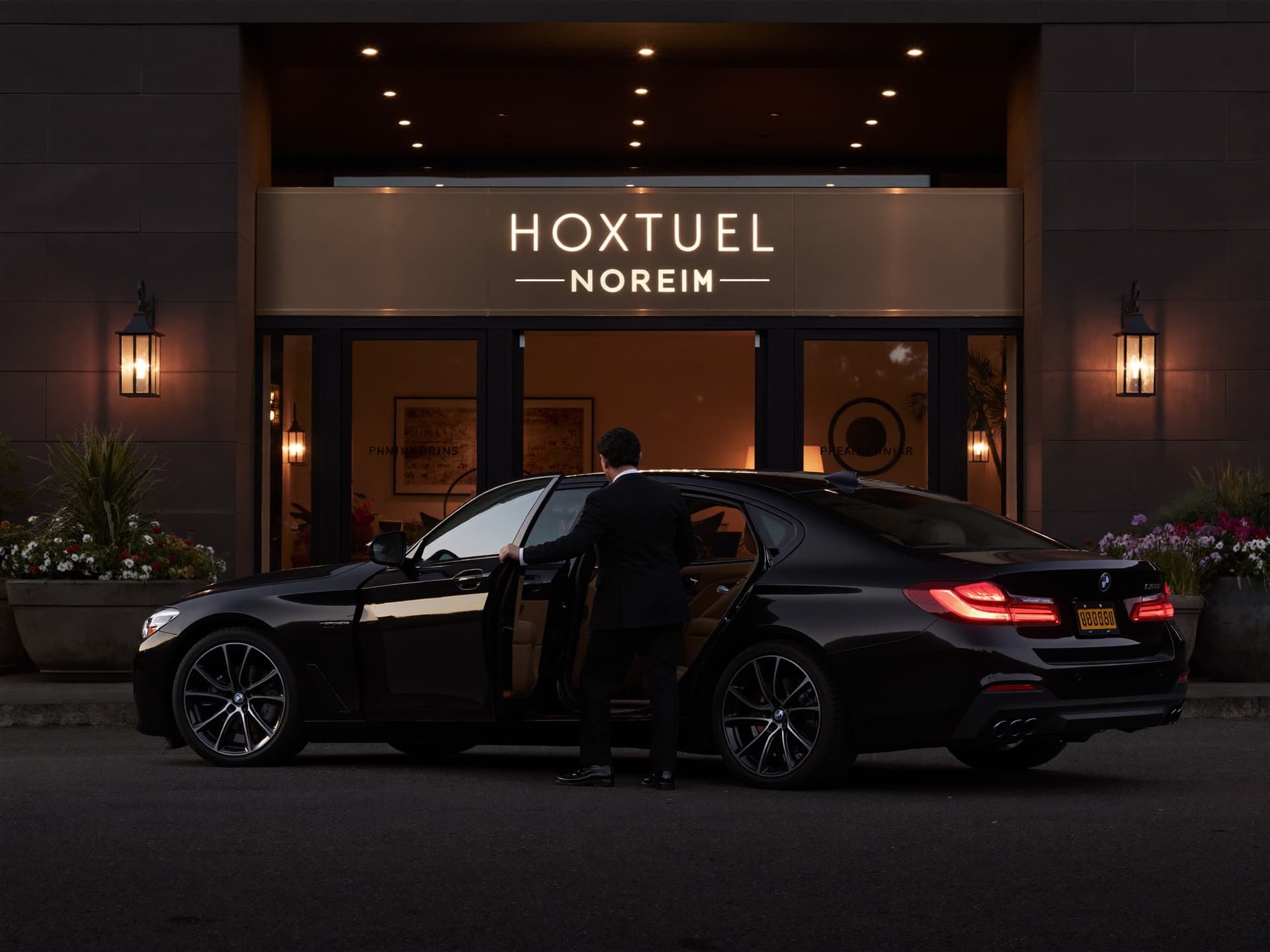 Chauffeur tenant la porte d'une berline noire devant un hôtel de luxe à Montréal